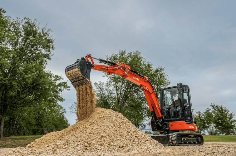 Excavator dumping dirt onto pile