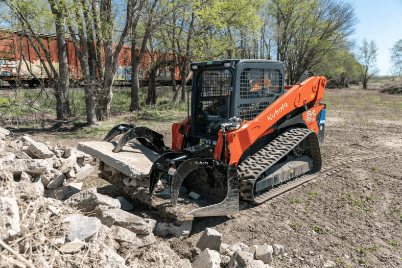 Loader using grapple bucket picking up cement blocks