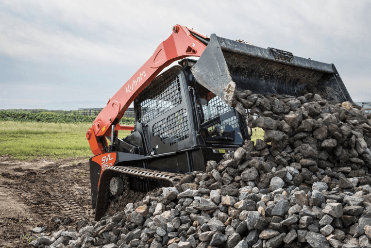 Track loader dumping large rocks