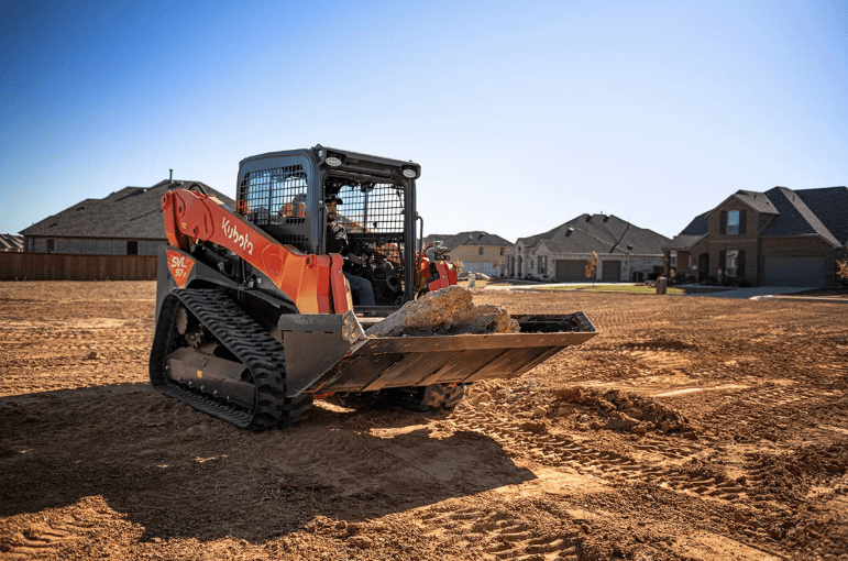 Man using track loader to move slabs of concrete