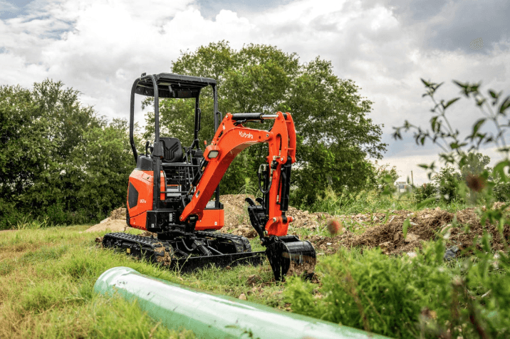 Compact Excavator picking up pipe