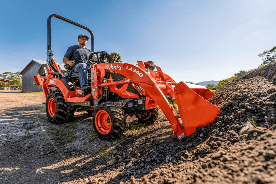 man scooping dirt on Kubota tractor