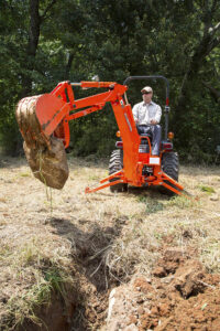 Man picking up boulder with Kubota B2301HSD-1 tractor from Mission Valley Kubota