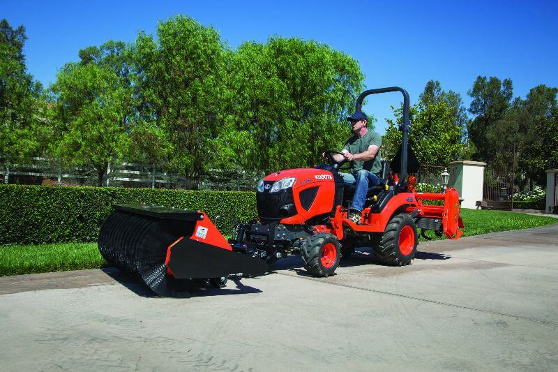 Man riding broom tractor from Mission Valley Kubota